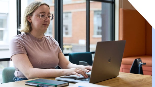 A focused professional woman working diligently on a laptop in an office setting