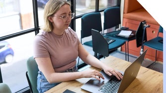 A focused professional woman working diligently on her laptop in a well-lit modern office setting