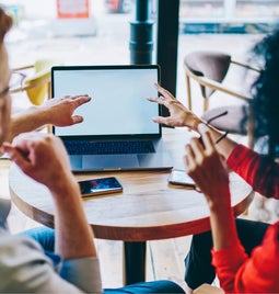 Two people pointing at a laptop