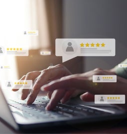 Person typing at a laptop with floating customer reviews around the hand