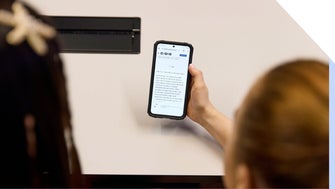 Over the shoulder view of two people looking at a smartphone displaying an article, sharing an interesting topic together.