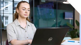 A focused professional woman works intently on her laptop in her business' office