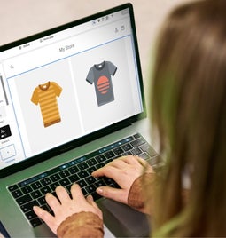 Person using an online store builder on her laptop to customize her t-shirt products on her ecommerce store