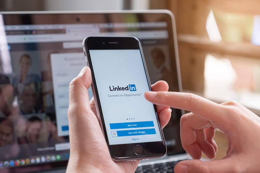 Person holding a mobile device with the LinkedIn login page on the screen