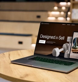 A laptop sitting open on a table in an office, with a Squarespace page open on-screen with the text 