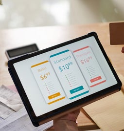 Tablet showing three subscription options with a person ready to pay holding the tablet