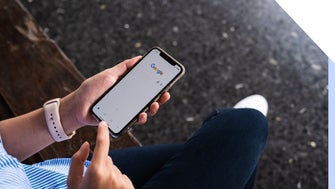 person using Google on phone while sat on a bench