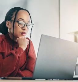 Woman sat and looking focused at the laptop in front of her