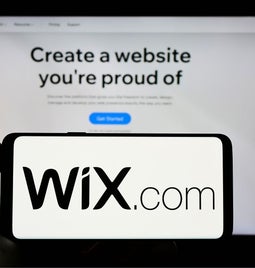 Photo of a mobile phone with the Wix logo in front of a laptop on the Wix website